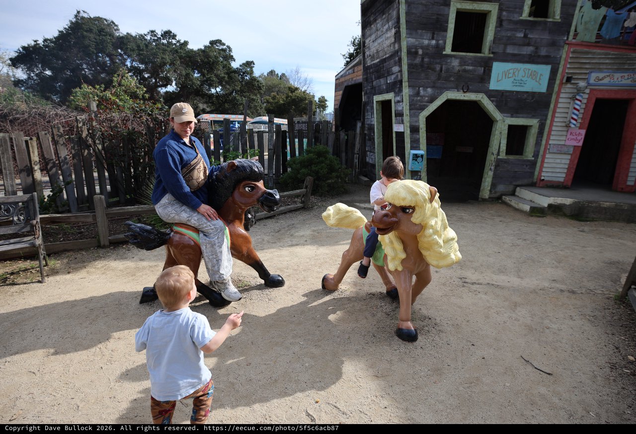 Children Enjoying Whimsical Horse Statues at Theme Park