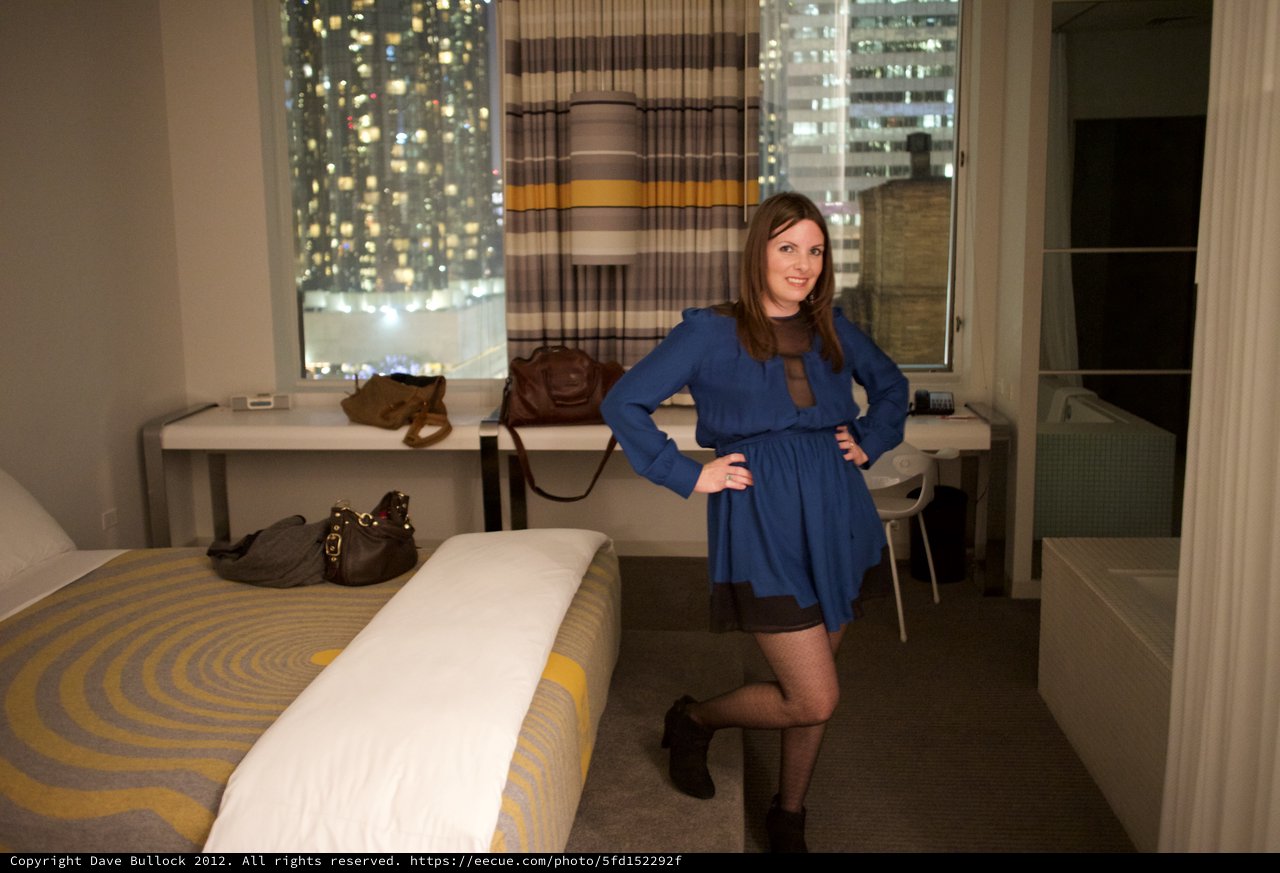 Woman in Blue Dress Poses in City Hotel Room
