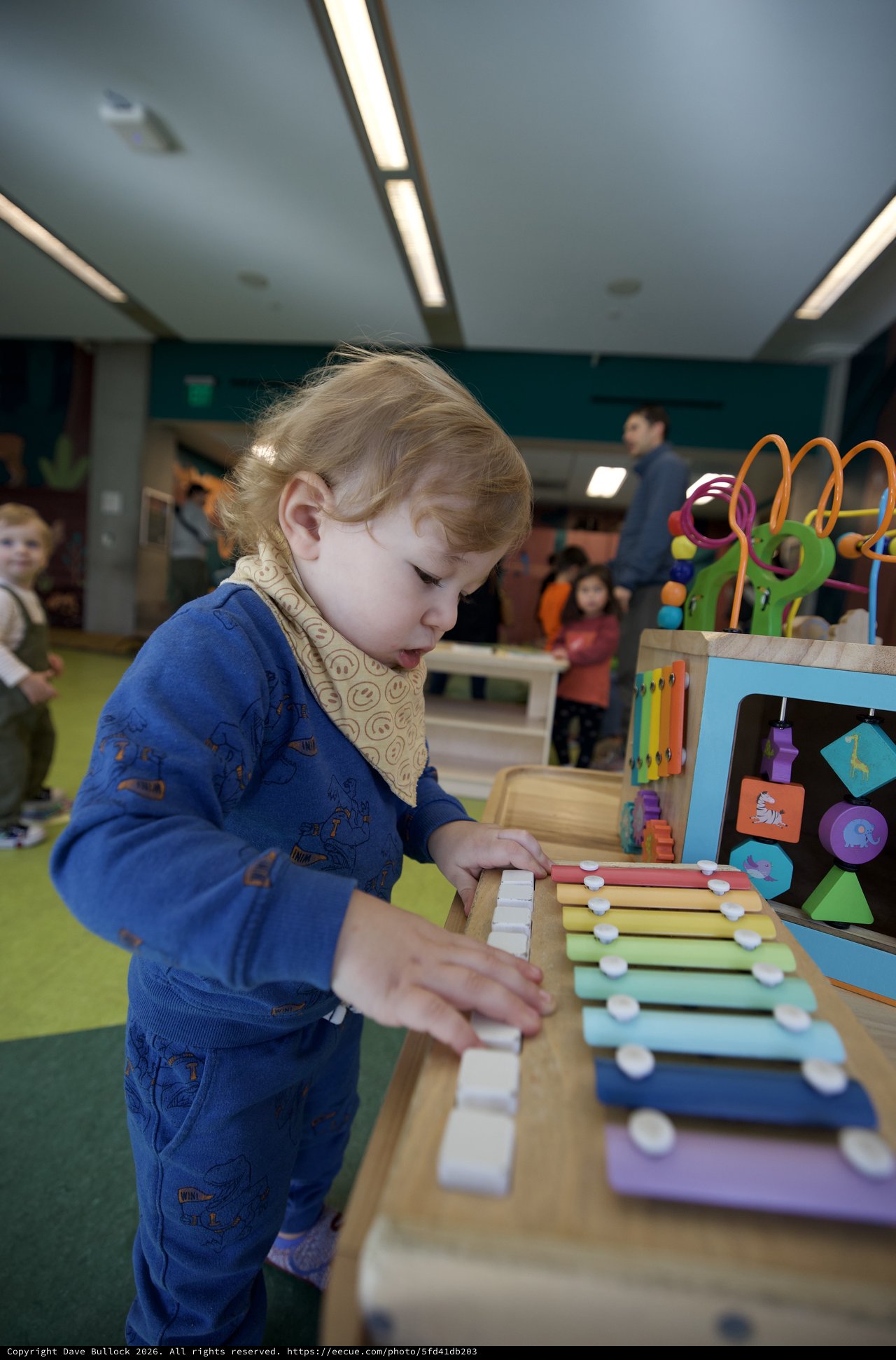 Young Child Exploring Musical Xylophone Toy at Play Center