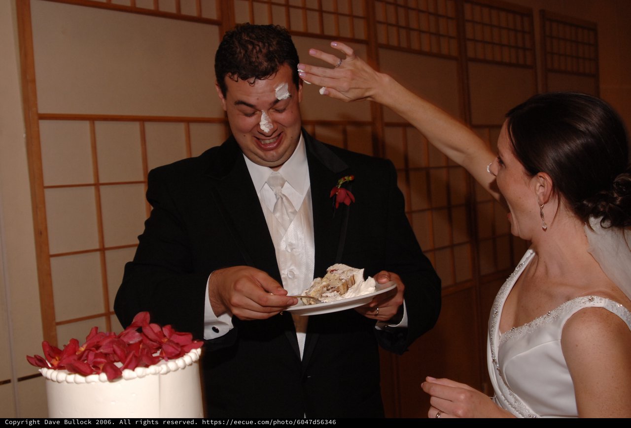 Playful Wedding Cake Smashing Moment at Reception