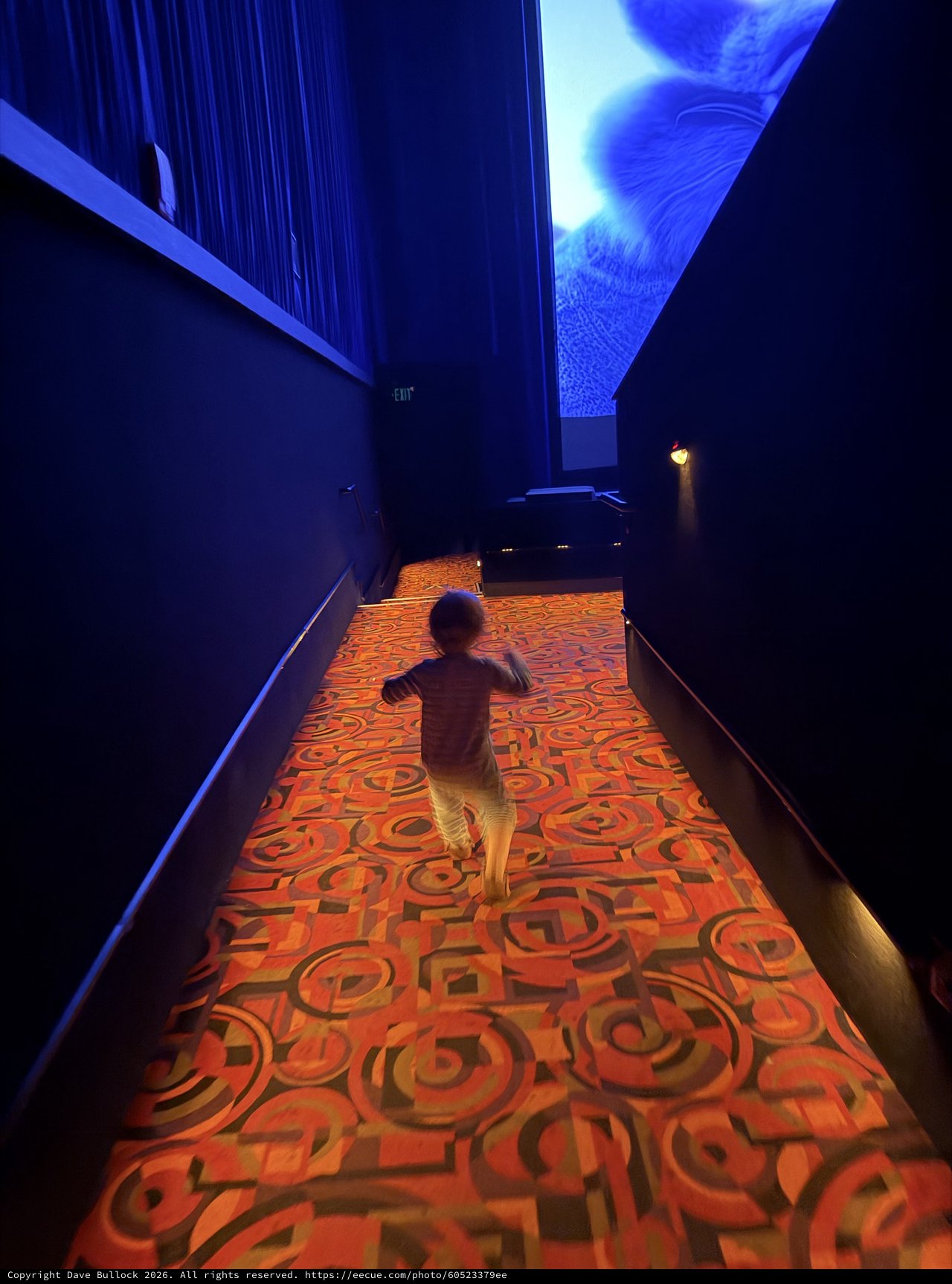 Child Running Through Illuminated Carpet Hallway in Dark Museum