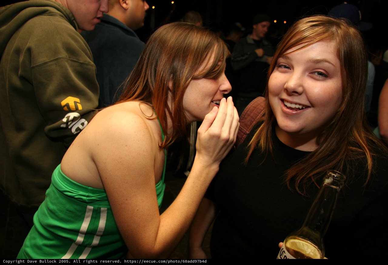 Two Friends Share a Secret at Nighttime Party