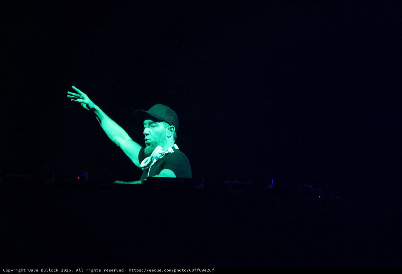 DJ Raises Hand Under Green Stage Lights at Wobbleland