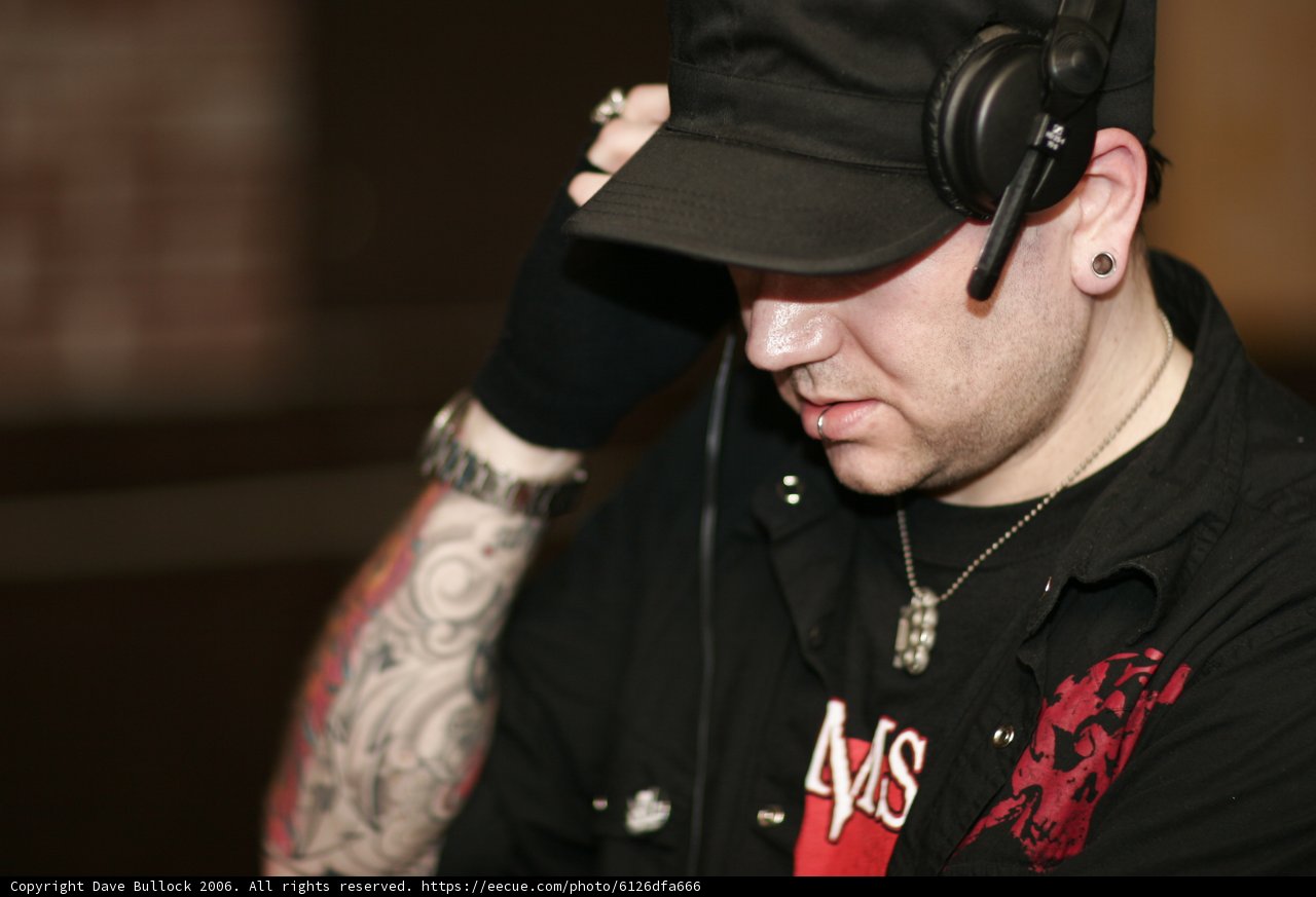 A Tattooed Man with Headphones and Baseball Cap