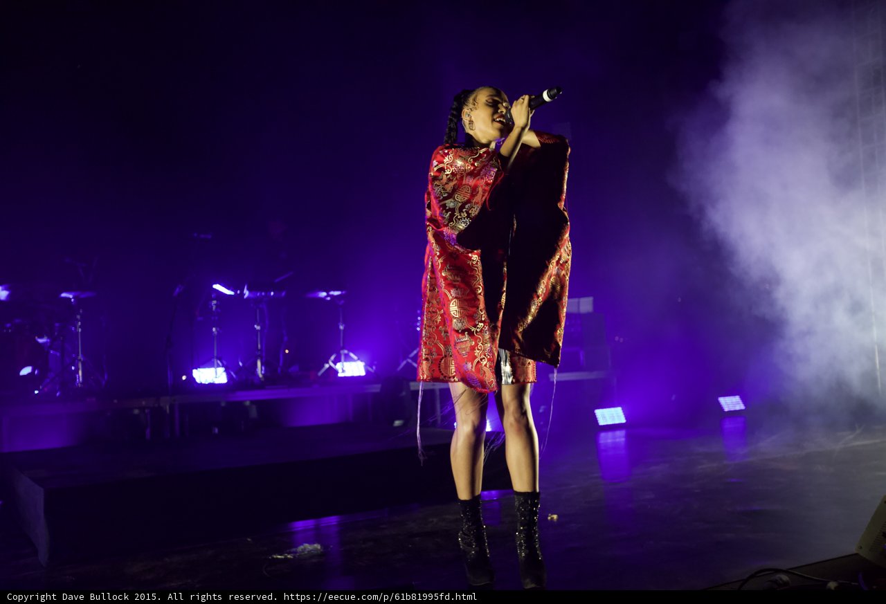 FKA twigs Full Body Singing Microphone Raised Looking Up Legs Apart Stance Kimono Red Brocade Gold Patterns Black Bodysuit Boots Purple Lighting White Haze LED Panels Band