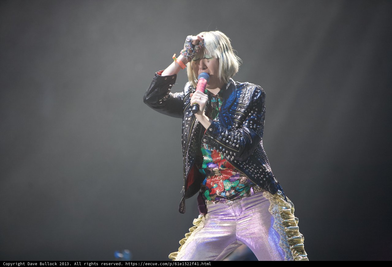 Colorful Solo Performance Caption: A female entertainer captivates the crowd with her vibrant outfit and powerful singing at Coachella 2013.
