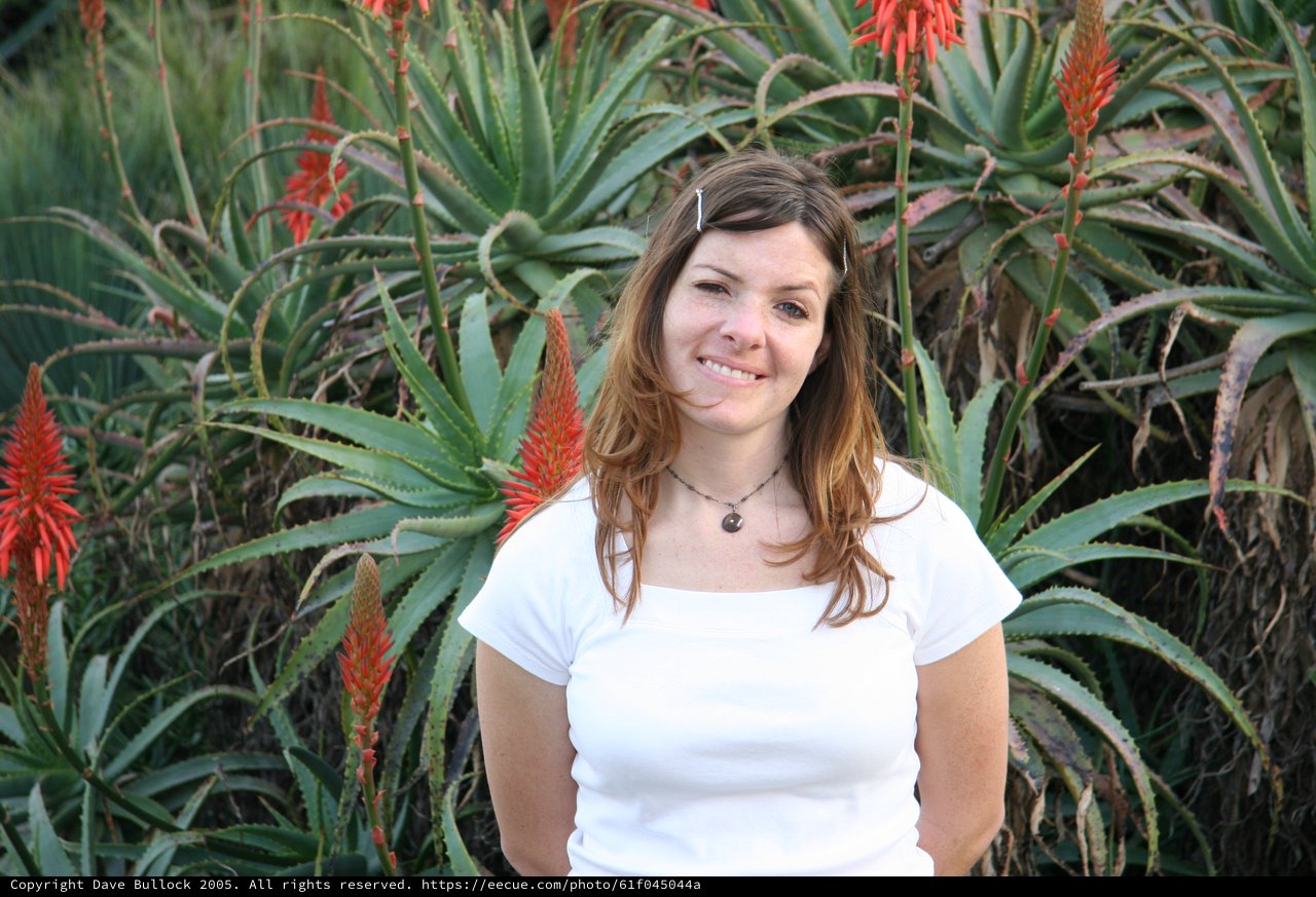 Young Woman Smiling Among Blooming Aloe Vera Plants