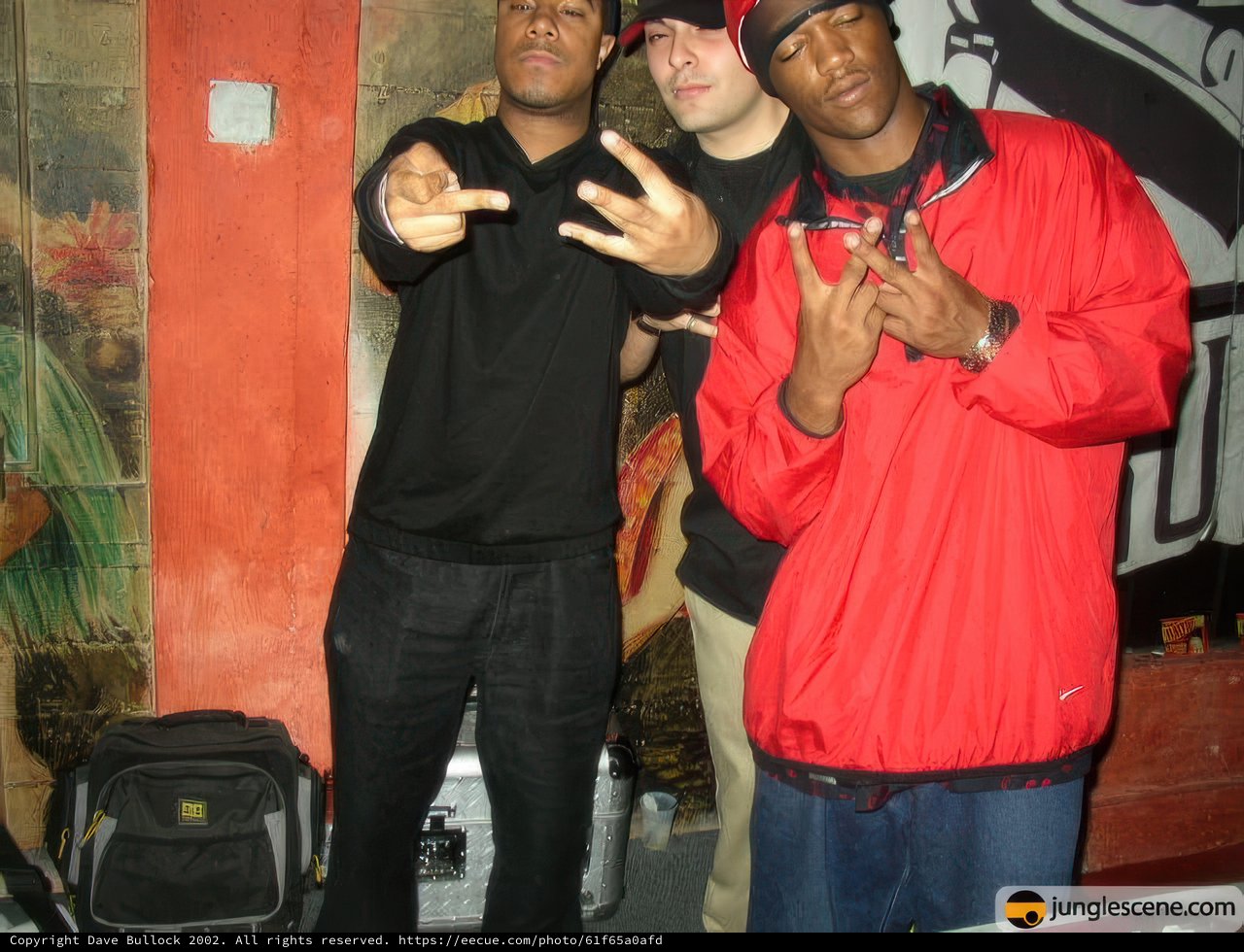 Three Men Posed in Front of a Wall