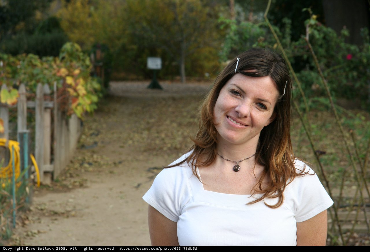 Smiling Young Woman in Autumn Garden Path
