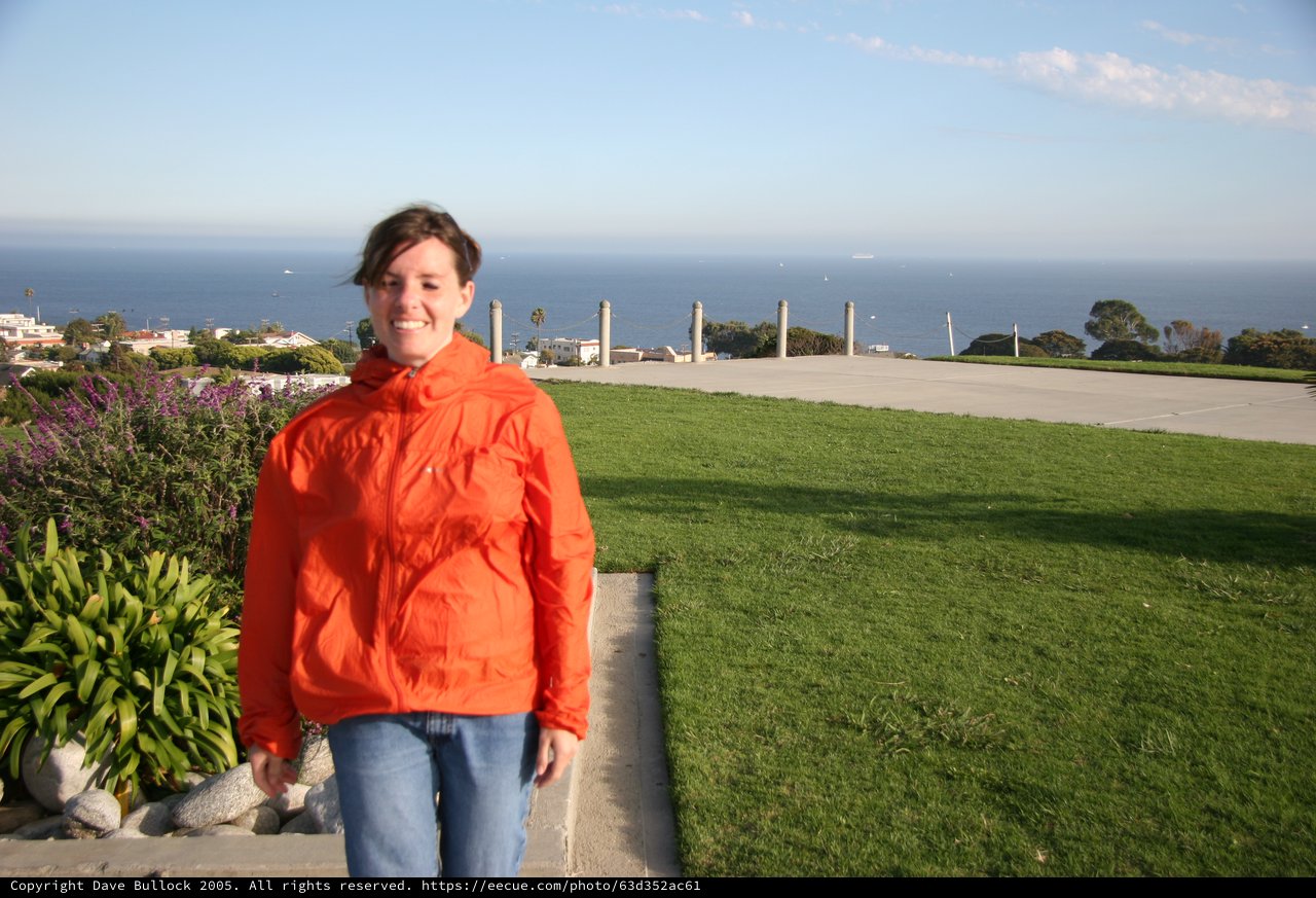 Smiling Woman in Orange Jacket by Coastal Overlook