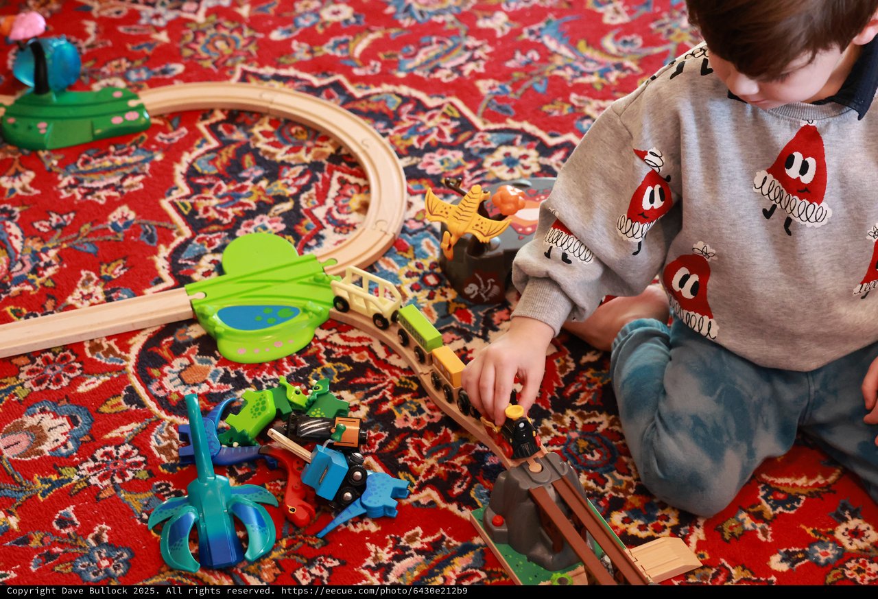 Child Playing with Wooden Train Set on Persian Rug