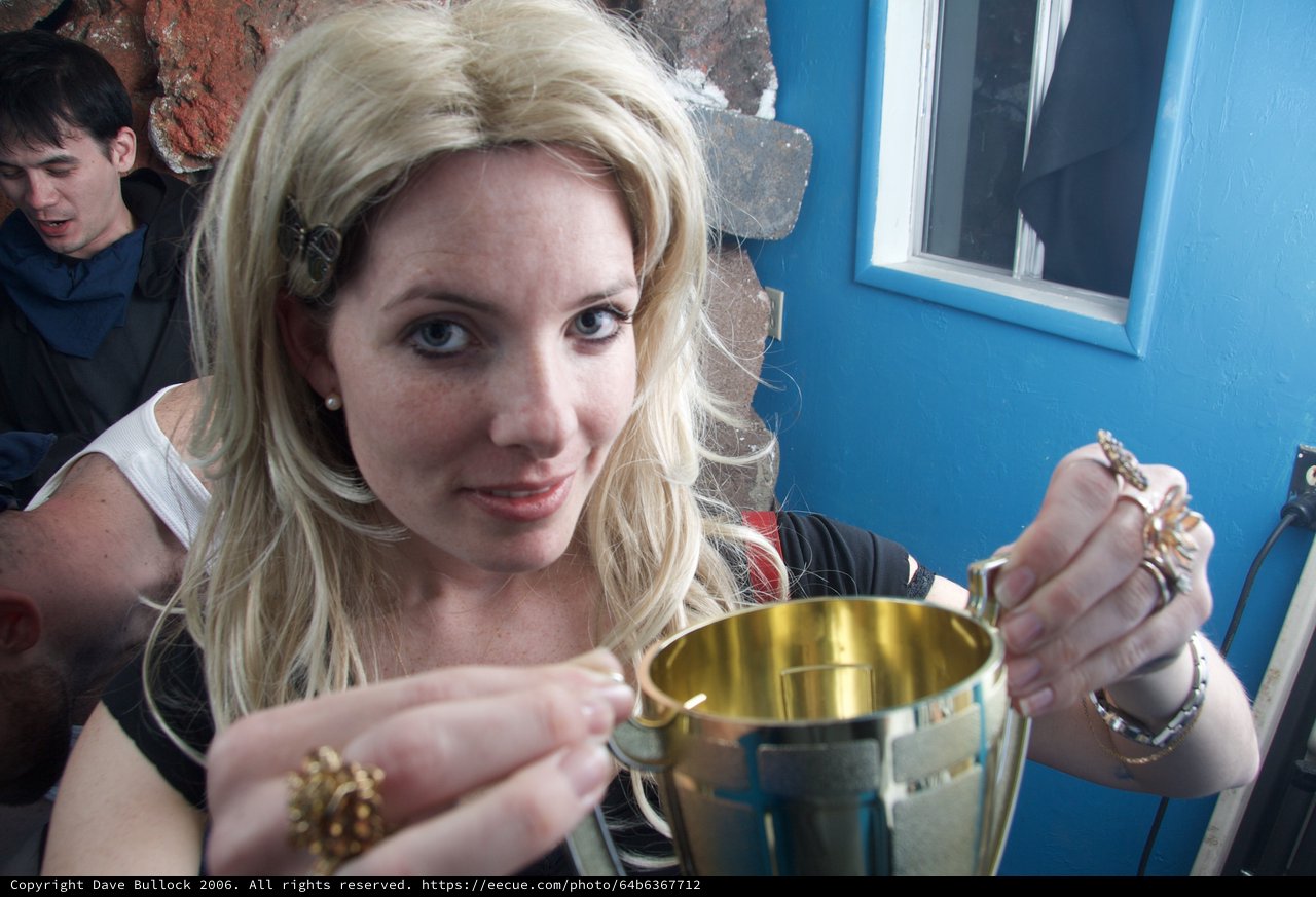 Woman Examines Golden Trophy at Halloween Gathering