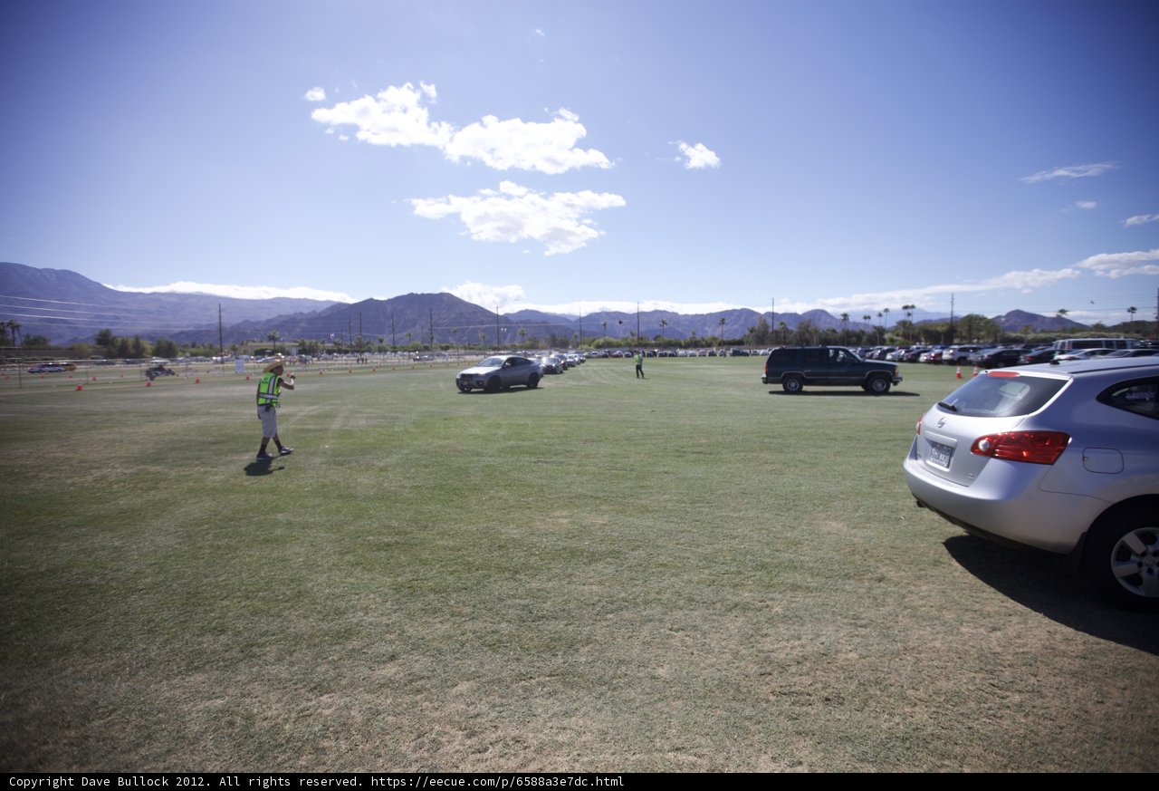 Kite-flying fun with a scenic view Caption: A person flying a kite in a grassy field with a mountain and a line of cars in the background during Coachella 2012.