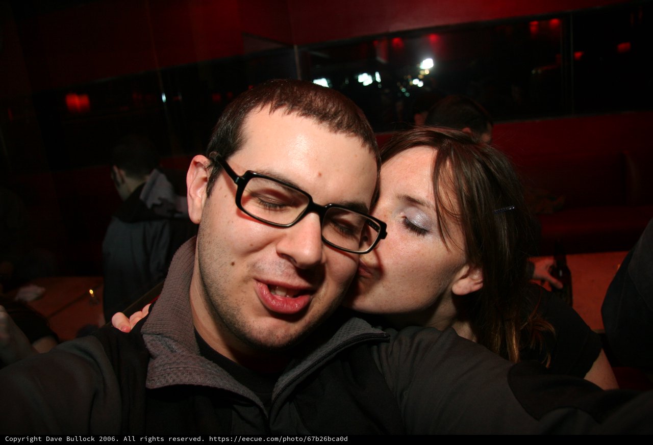 Spontaneous Kiss at a Dimly Lit Nightclub Party