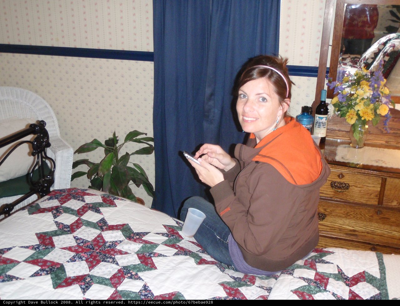Woman Texting on Patchwork Quilt in Cozy Bedroom