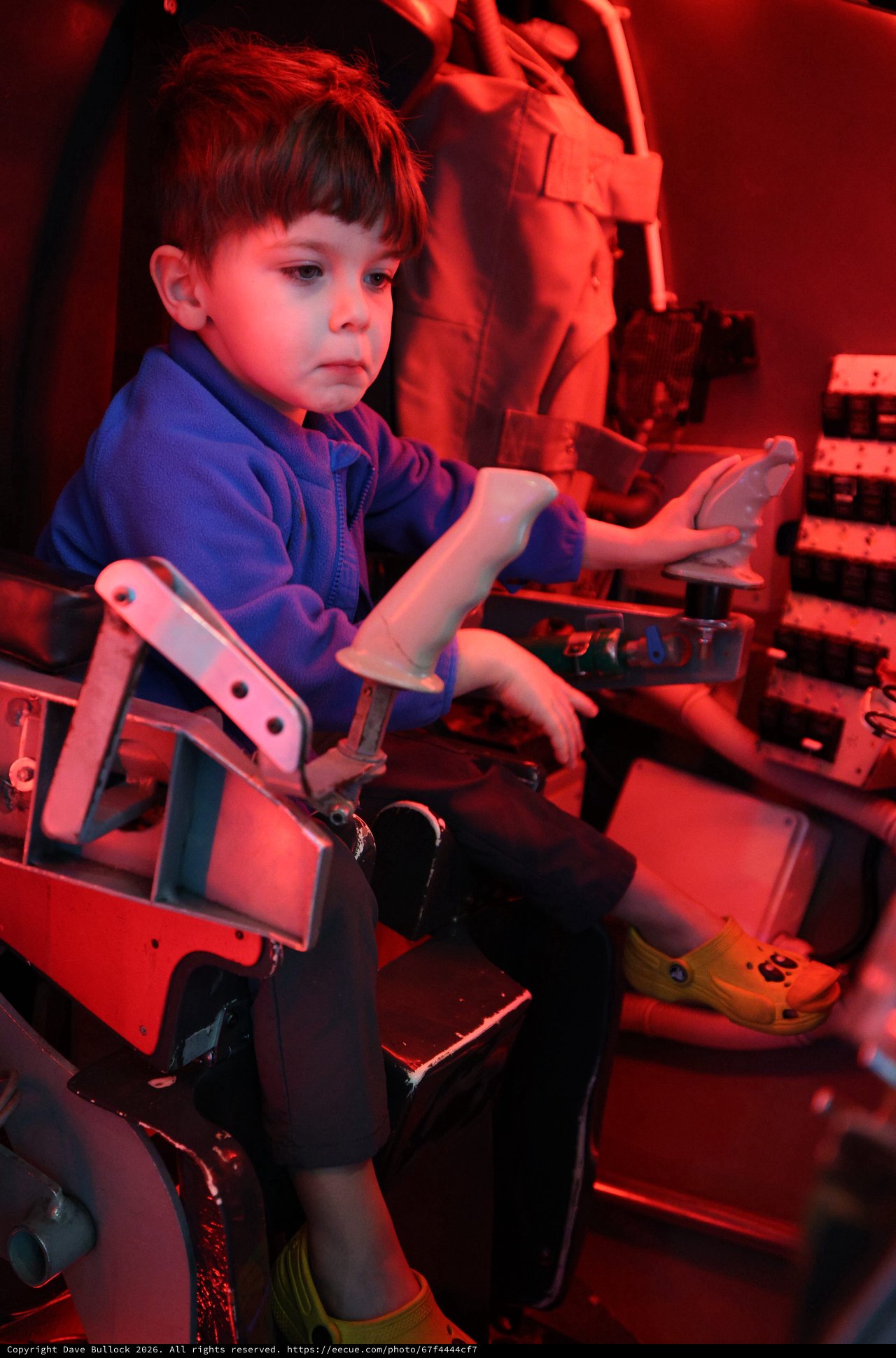 Young Boy Exploring Interactive Exhibit Under Red Lighting