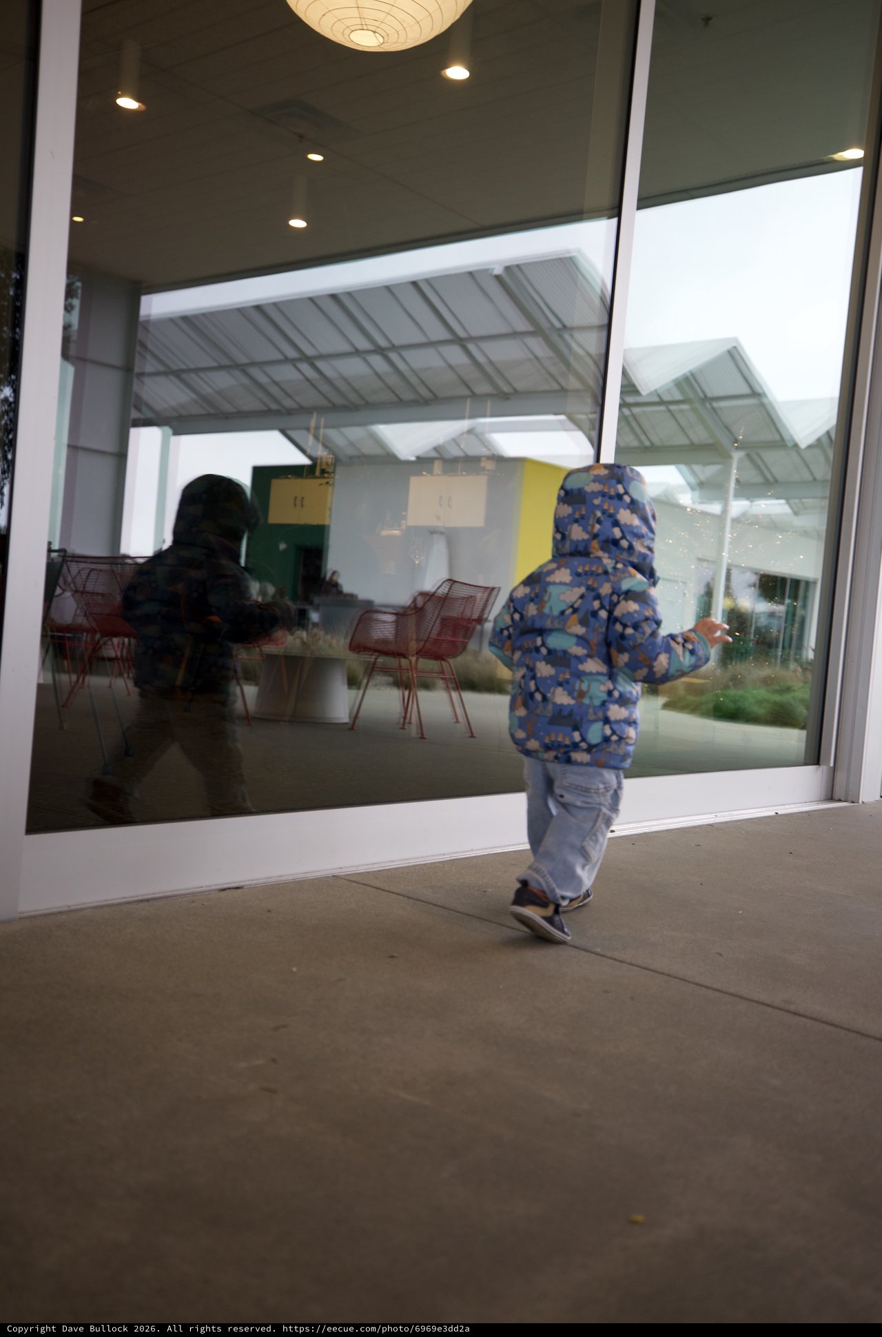 Child Explores Modern Restaurant Through Glass Door
