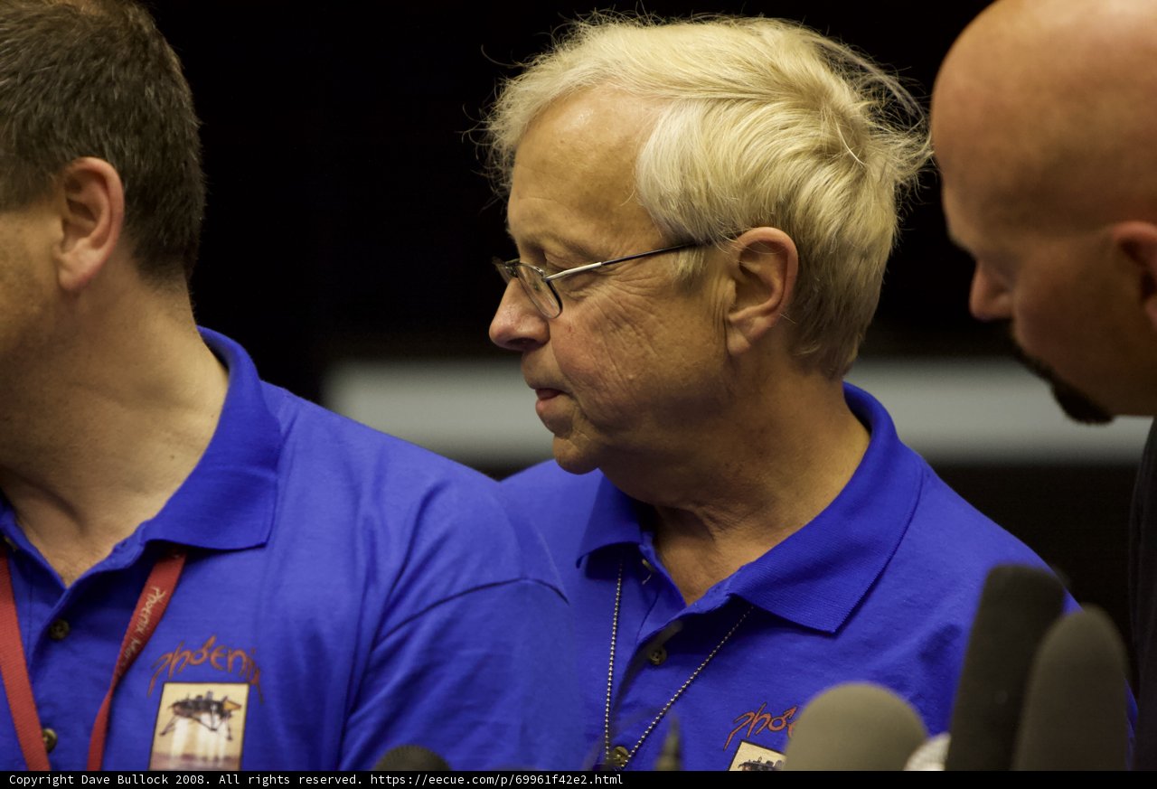 Three Men in Blue Glasses Contemplate Optical Equipment