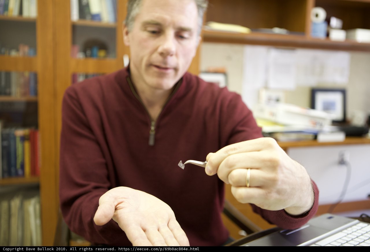Hand holding a small electronic device in a library