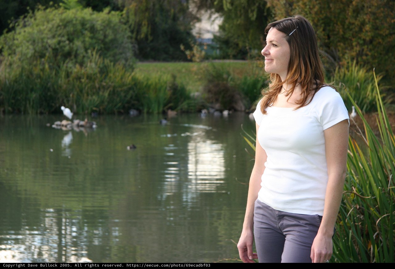 Woman Gazing Peacefully by a Tranquil Park Pond