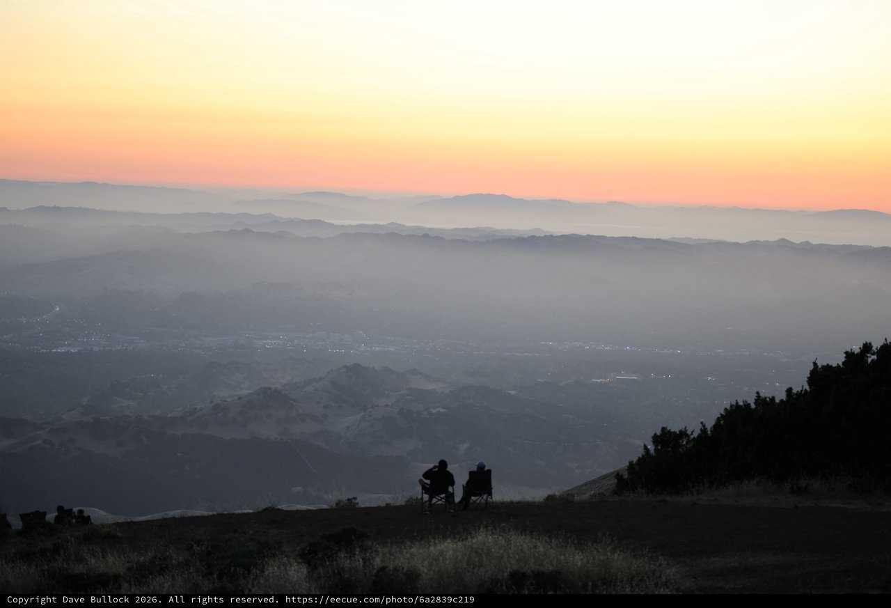 Silhouetted Couple Watches Sunset Over Misty Valley