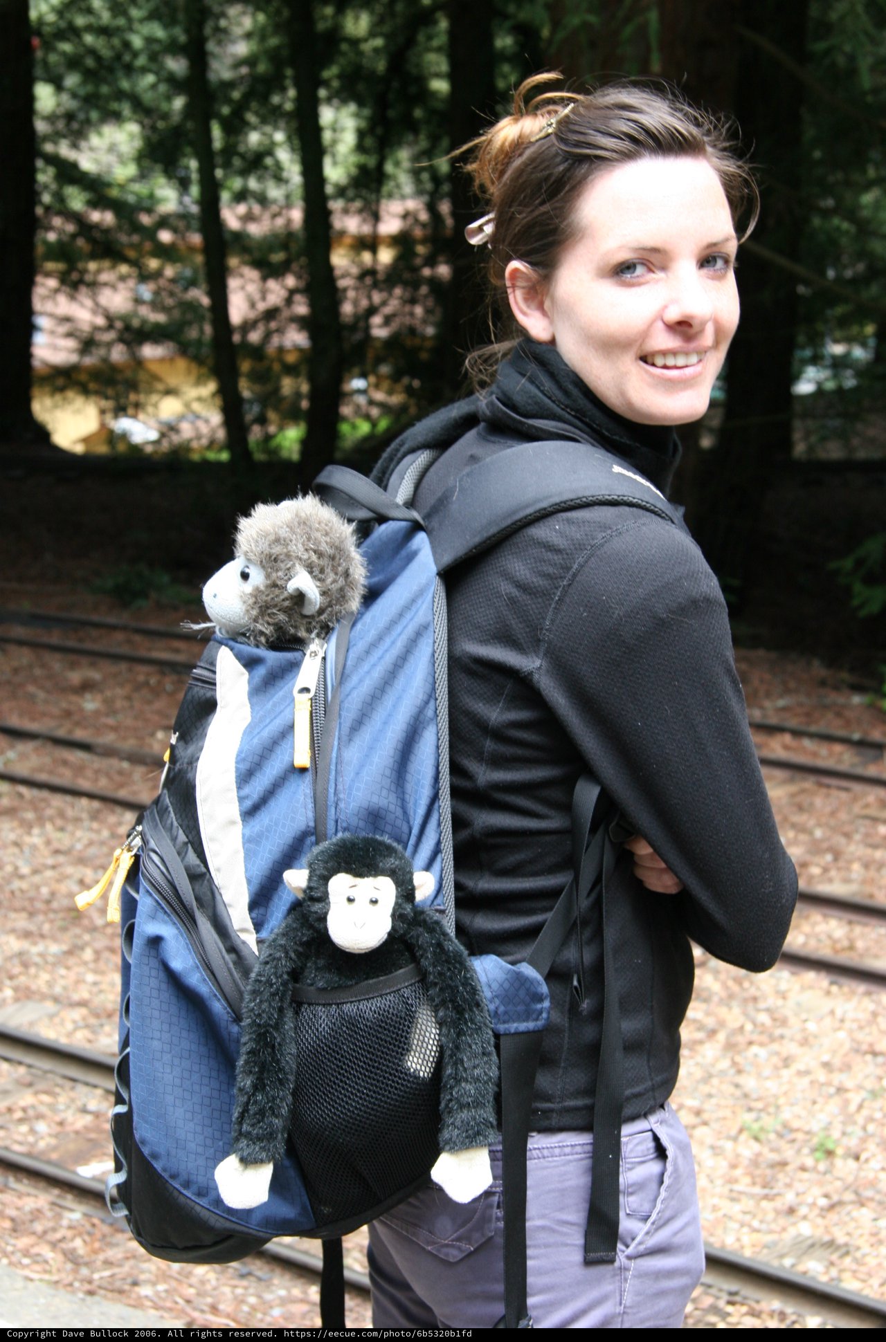 Smiling Woman with Stuffed Monkey Backpack Companions