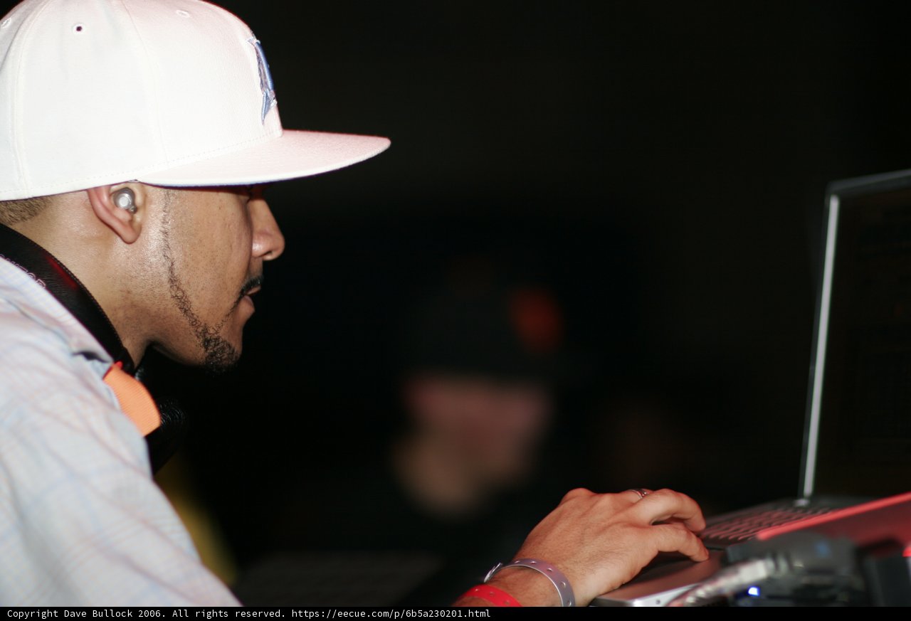 Man in a White Hat Typing on a Laptop