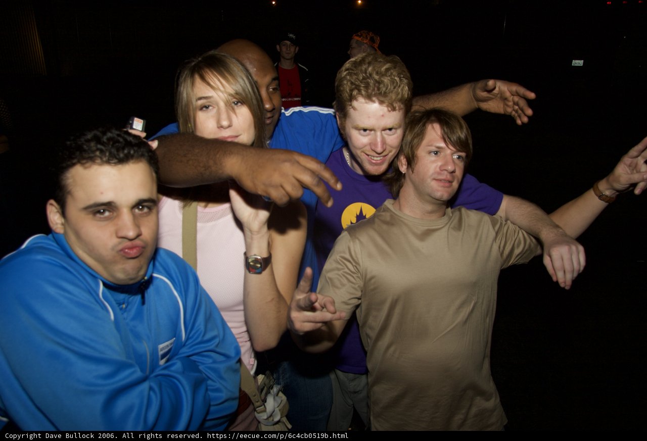 Group of Three Men with Colorful T-Shirts Posing for Picture at Night Club
