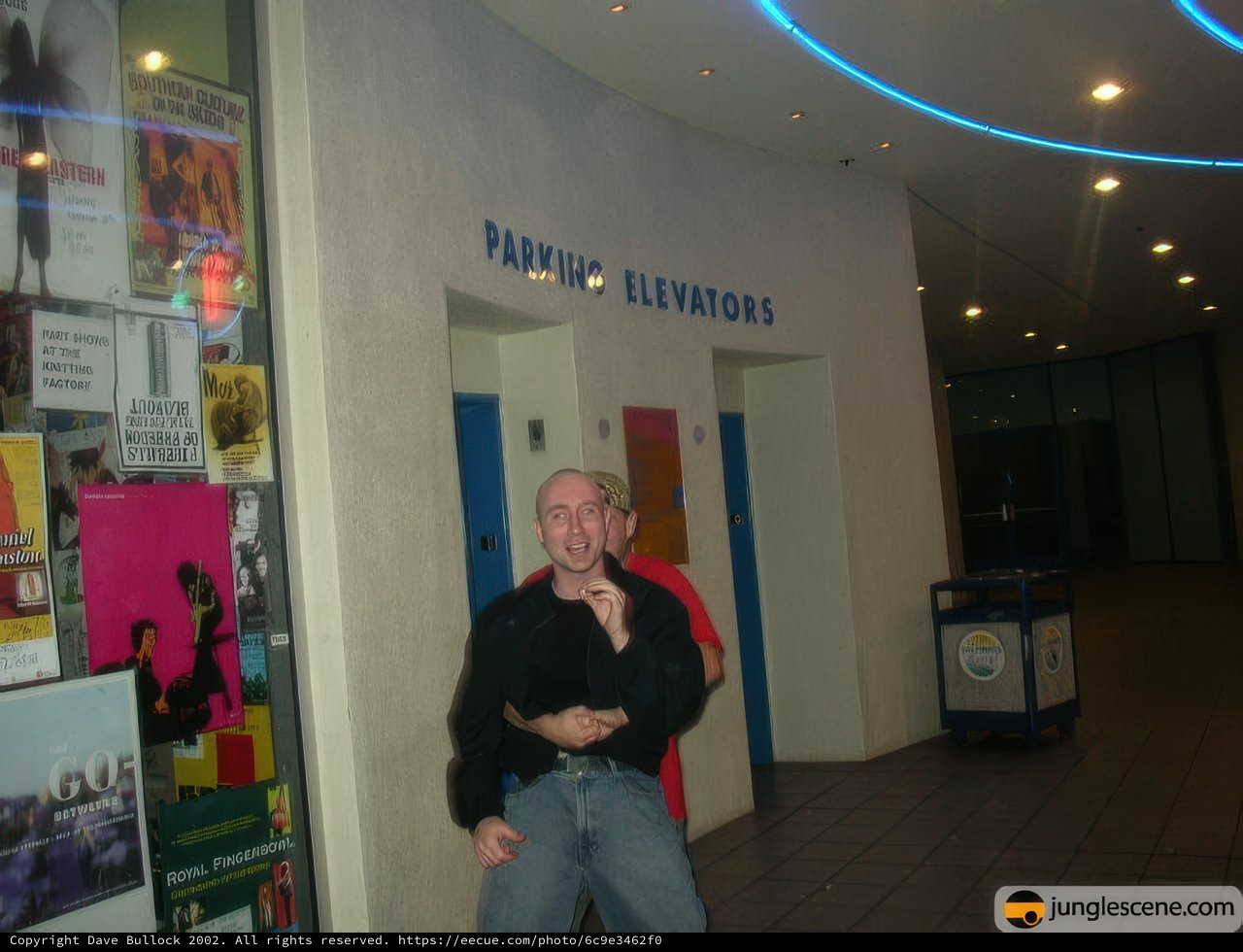Man posing in front of a building with a sign