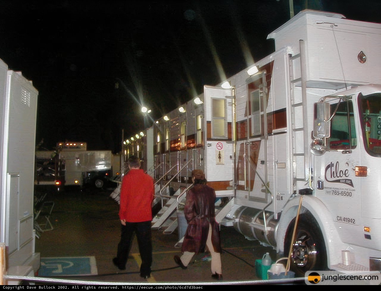 Three People Walking by White Semi Truck at Night