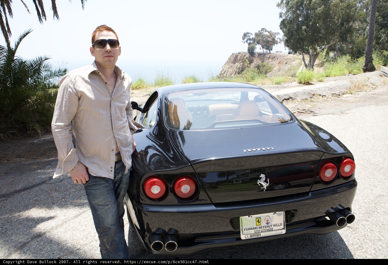 Man Poses Next to Sleek Black Sports Car