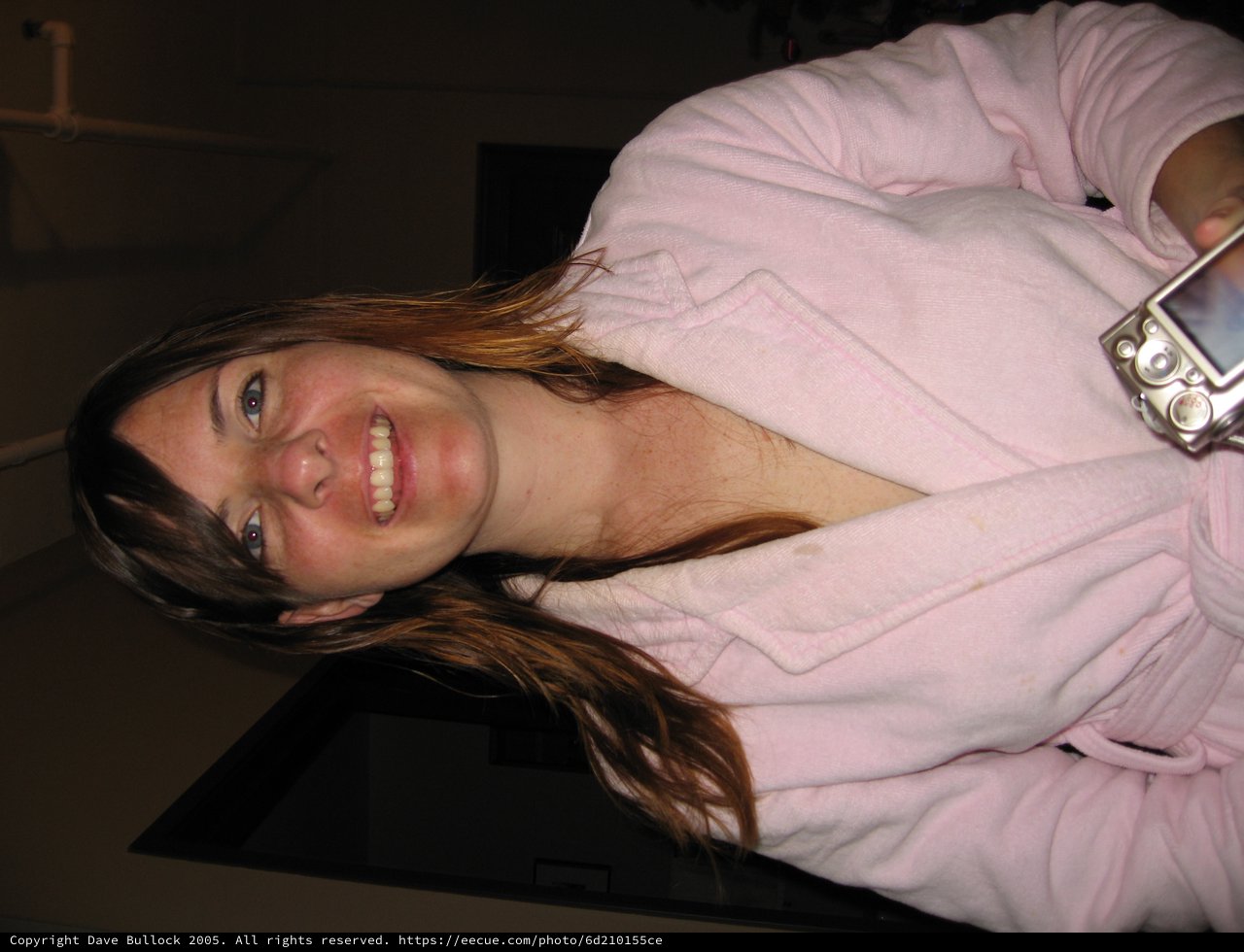 Smiling Woman in Pink Robe Holding Camera