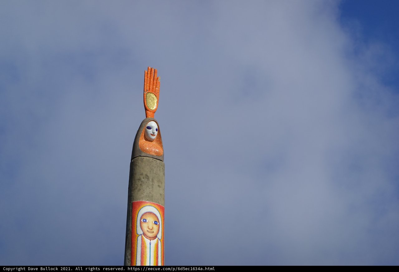 Totem Pole with Painted Face Against Clock Tower Building