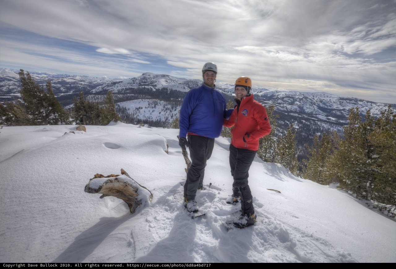 Summit Triumph: Couple Atop Snow-Covered Mountain Peak