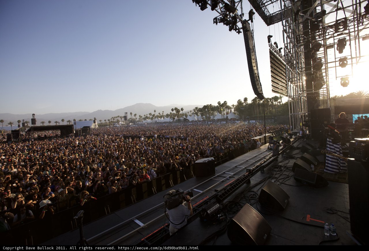 Coachella 2011: Music Fans Rock Out Caption: Mamatha Maben and Rosanna Arquette join thousands of music fans at Coachella 2011's Friday lineup. The outdoor concert features four massive speakers, two glasses and plenty of accessories, with a beautiful blue sky, tree-covered hill and land as the backdrop.