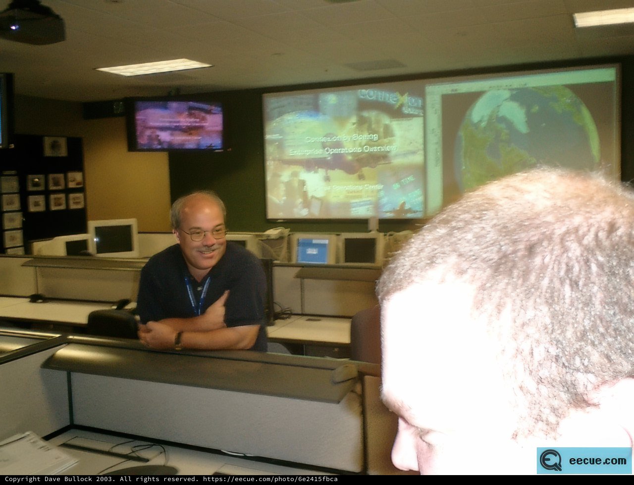 Man in Blue Shirt Multi-Tasking on Three Screens