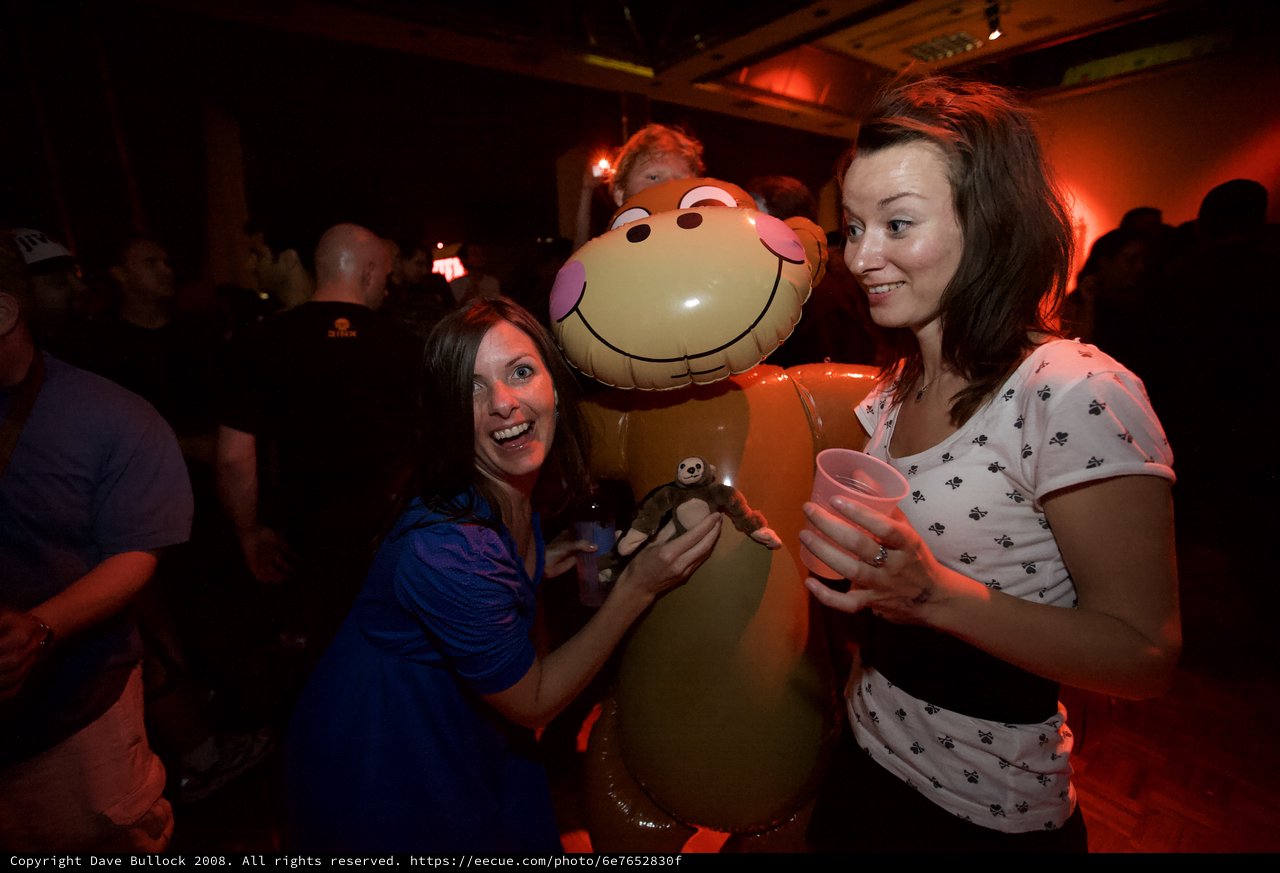 Two Women Laughing with Inflatable Monkey at Party
