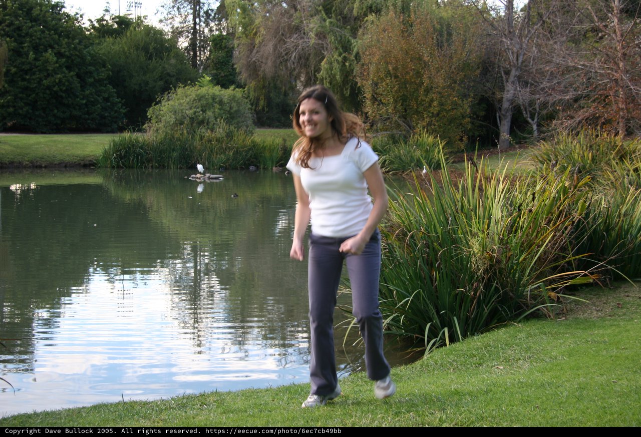 Woman Smiling by Tranquil Park Pond at Dusk