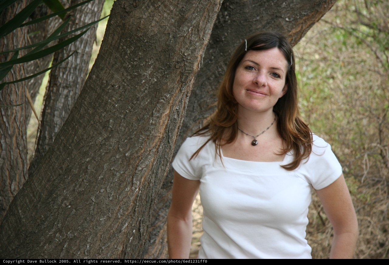 Woman Smiling Beside a Tree in Nature