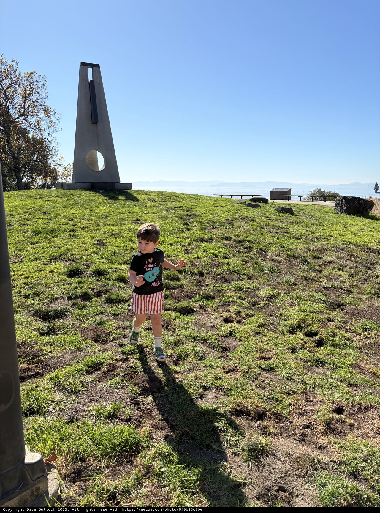 Child Exploring Near Modern Monument on Hillside