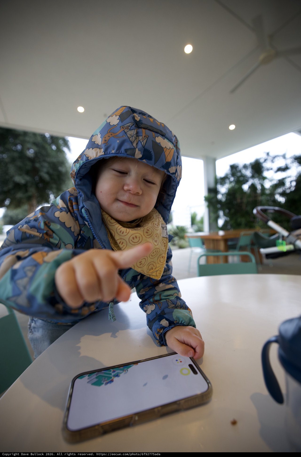 Young Child Engaging with Smartphone at Outdoor Table