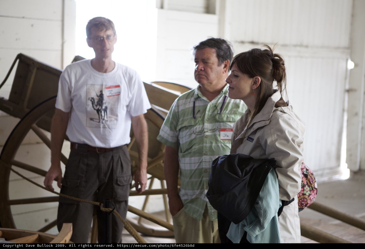 Three Visitors Examine Historic Wagon at Museum