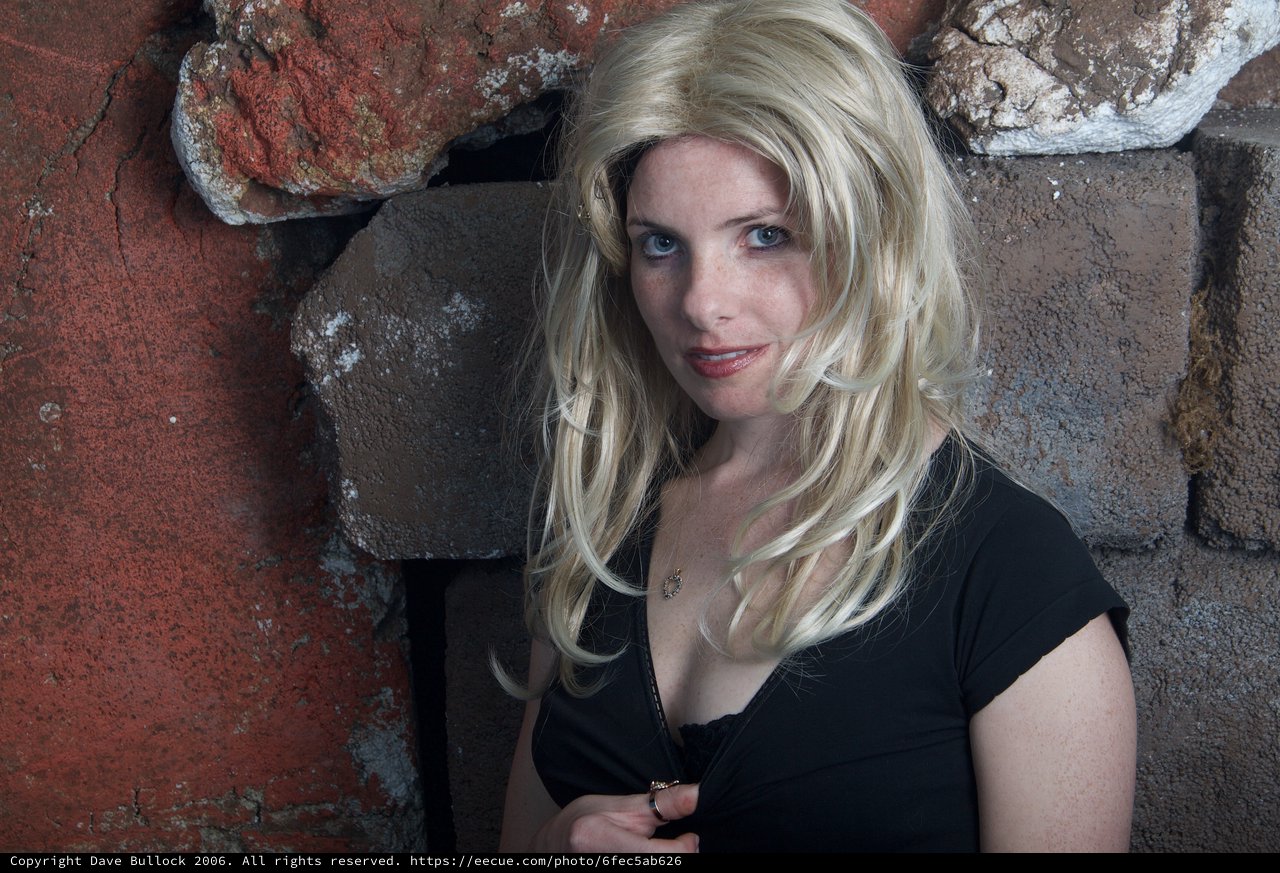 Blonde Woman Poses Against Rustic Stone Wall