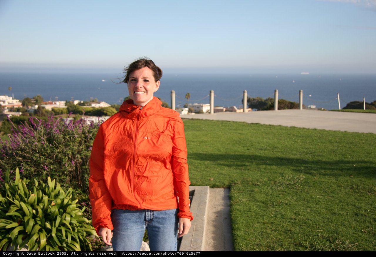 Smiling Woman in Orange Jacket by the Sea