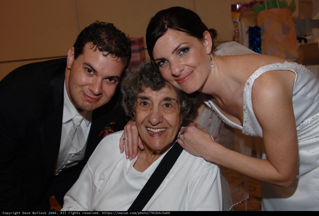 Bride and Groom Embrace Beloved Grandmother at Wedding