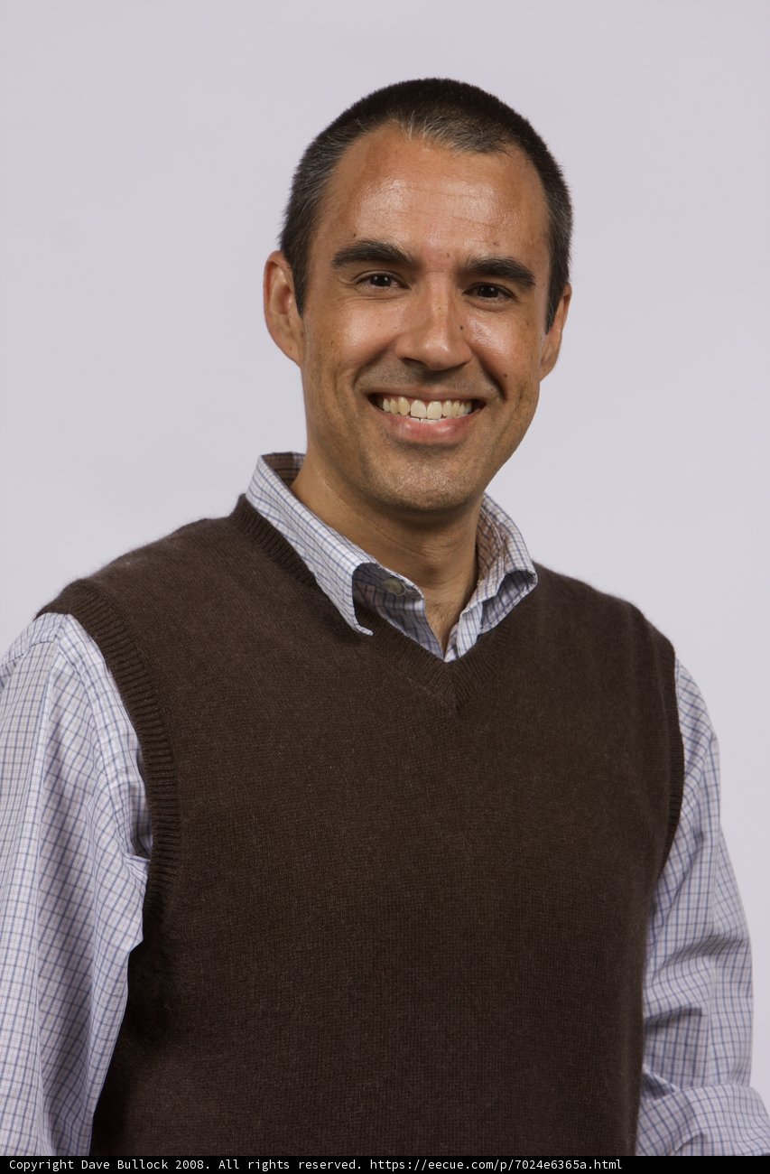 The Happy Man in a Sweater Vest Caption: This 2008 APC photoshoot captures a man in a brown sweater vest and white shirt, smiling and laughing for the camera, showcasing his cheerful personality and stylish outfit.