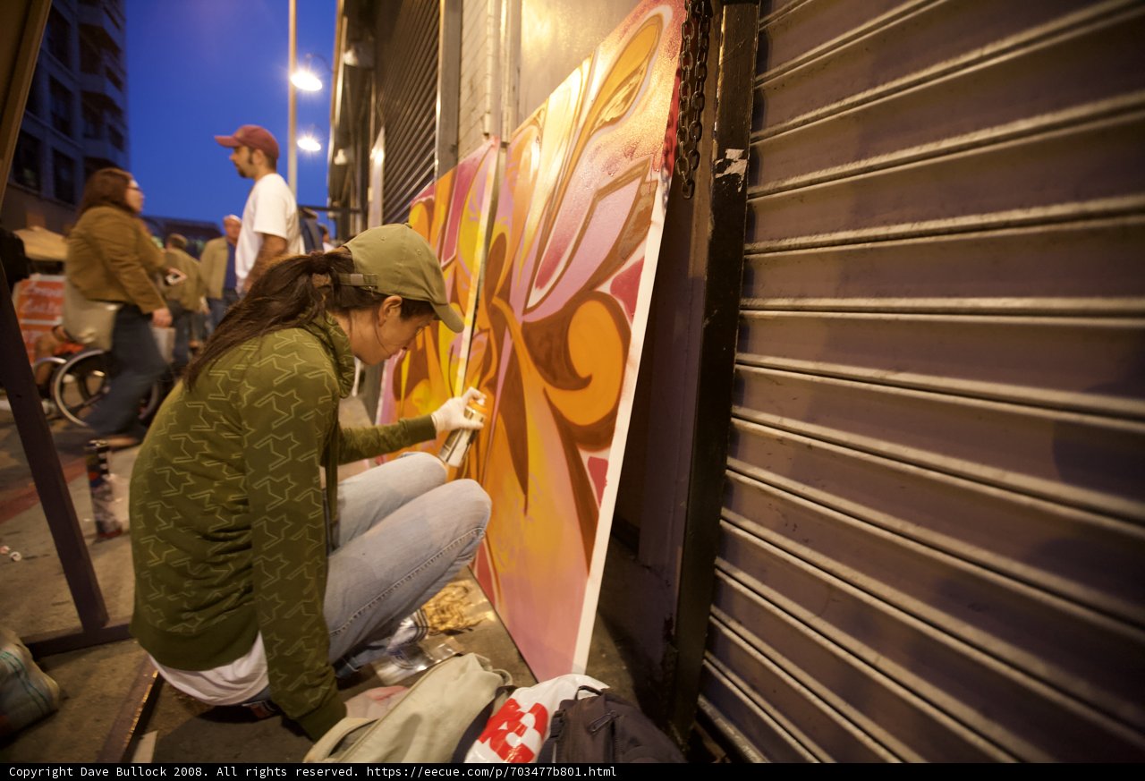 Urban Artistry: A Woman Painting a Mural on the Side of a Building