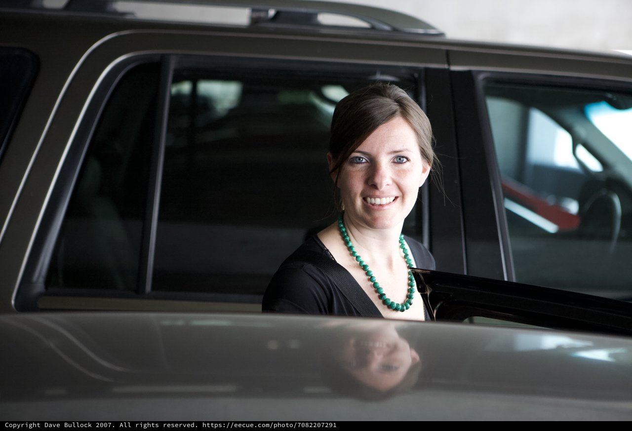 Smiling Woman Beside a Grey SUV in Parking Area
