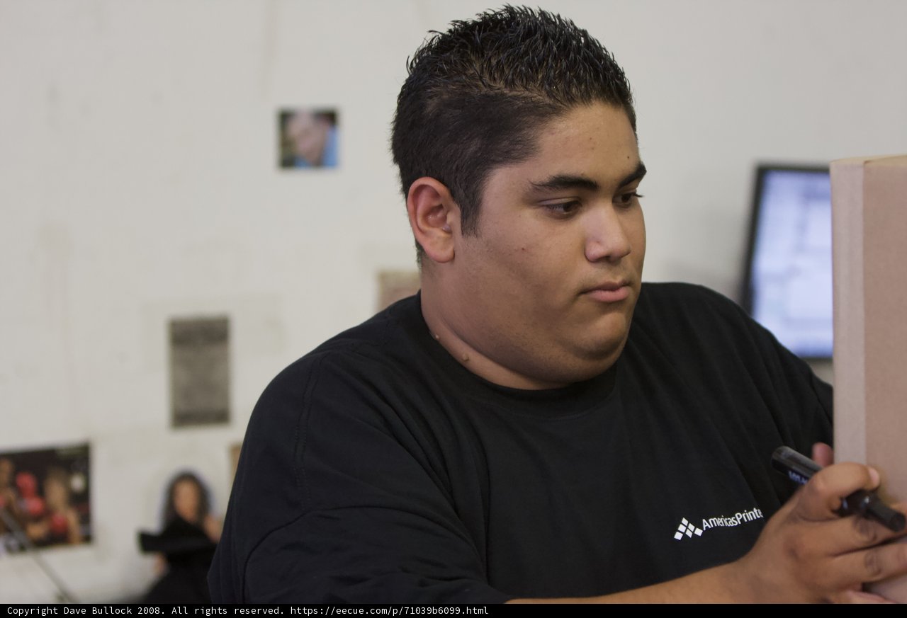 Man Holding Paper in Front of Monitor
