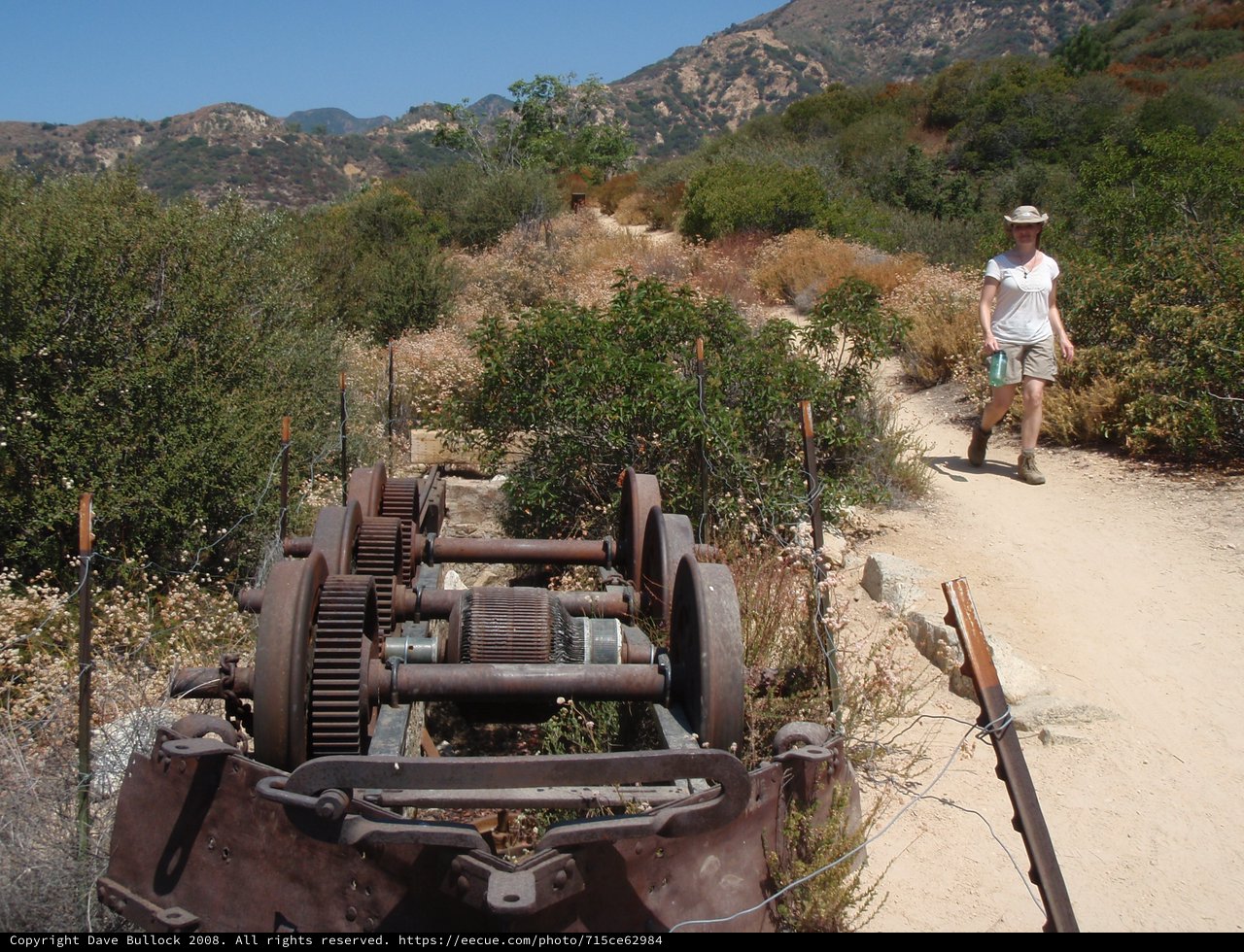 Hiker Passes Rusted Mining Equipment on Desert Trail